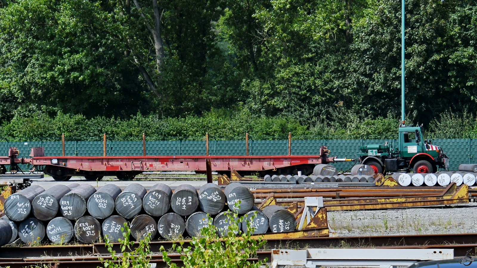 Mitte August 2024 habe ich in Hattingen bei einem Blick durch den Zaun der Firma Kerkemeier diesen an einem Zweiwege-Unimog gehängten Flachwagen (Samms, 31 80 4952 560-0) entdeckt.