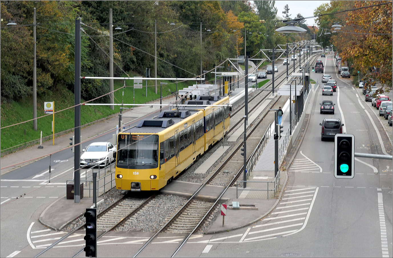 Saniert und verlängert - 

... wurde die Haltestelle Nürnberger Straße im Rahmen des Ausbaus der Stuttgarter Stadtbahnlinie U1 für Doppelzüge. Dabei erhielt die Haltestelle auch auf der östlichen Seite einen Zugang, was für Anwohner in diesem Bereich den Weg zur Stadtbahn verkürzt. Während die alte Überdachung stufenförmig auf das Gefälle reagiert, sind die Überdachungen auf dem verlängerten Abschnitt hingegen durchgehend auf einer Ebene. 

Teil des Ausbaus der Strecke ist auch die Erneuerung der Fahrleitungsanlagen. Bislang war die Hochkettenfahrleitung an Masten am Straßenrand aufgehängt, jetzt übernehmen Masten zwischen den Gleisen diese Aufgaben. Für Fotografen wird dadurch der freie Blick auf die Strecke eingeschränkt.

24.10.2024 (M)

 