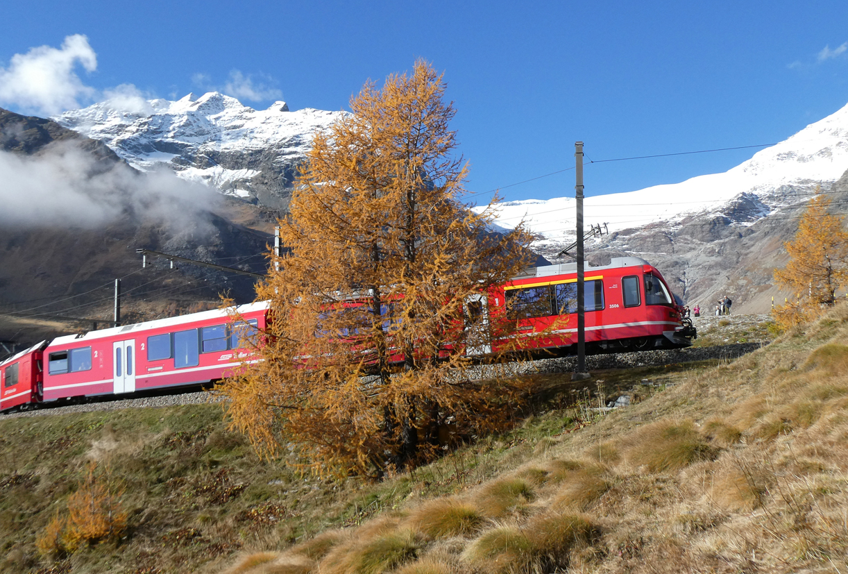 Ungewohnte Perspektive: Triebzug 'Allegra' 3504 fährt mit dem Regionalzug von Tirano nach St. Moritz auf der Haarnadelkurve in den Bahnhof Alp Grüm (2091 müM) ein, währenddem rechts die Fahrgäste des Bernina-Express diesen Vorgang verfolgen. Im Hintergrund ist ein Teil des Palügletschers zu sehen. Alp Grüm, 22.10.2024