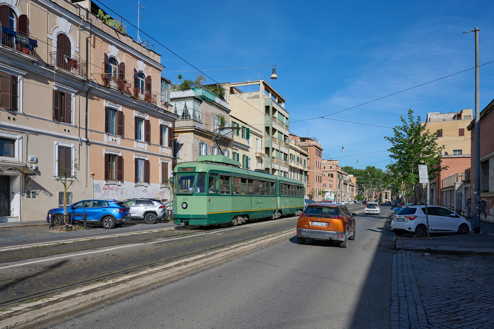 Wagen 7077 der Straßenbahn Rom war am 05.05.2024 auf der Linie 5 unterwegs von der Piazza dei Gerani zum Bahnhof Termini. Gerade hat der Wagen die Haltestelle an der Porta Maggiore verlassen, welche im Hintergrund zu sehen ist, und befand sich in der Via di Porta Maggiore.
(Autokennzeichen ist verändert)  