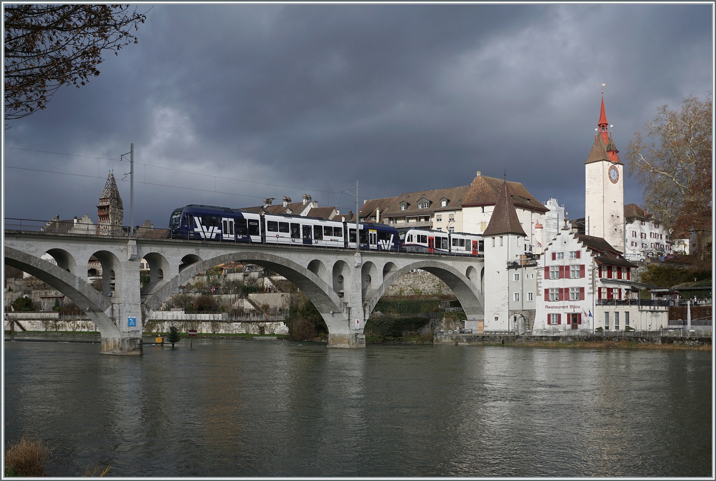 Zwei AVA BDWM Abe 4/8  Diamant  in unterschiedlicher Farbgebung sind als S17 kurz nach der (während des Weihnachtsmarktes nicht bedienten Haltestelle) Bremgarten Obertor bei geradezu dramatischen Lichtverhältnissen auf der Fahrt von Dietikon nach Wohlen und überqueren dabei die fotogene 156 Meter lange Reussbrücke. 

6. Dezember 2024