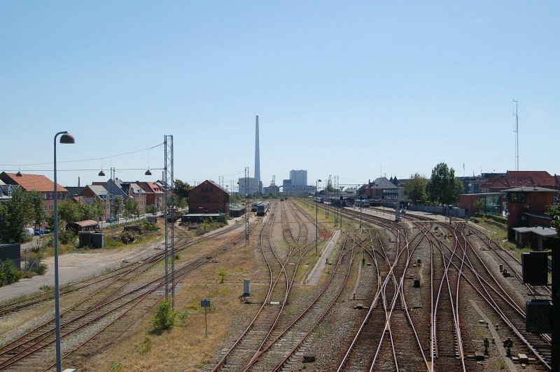 Blick ber das Bahnhofsgelnde von Esbjerg. Der Bahnhof von Esbjerg ist ein Kopfbahnhof. Frher fuhren die Personenzge noch bis zum Hafen an den Fhranleger fr die Fhren nach England. Heute fahren nur noch vereinzelt Gterzge in den Hafen. Der Hafen ist auf dem Bild duch den hohen Turm des Kohlekraftwerkes zu erkennen. Von Esbjerg kommt man jede Stunde nach Kopenhagen, Skjern, Varde, Tnder und Fredericia. August 2007