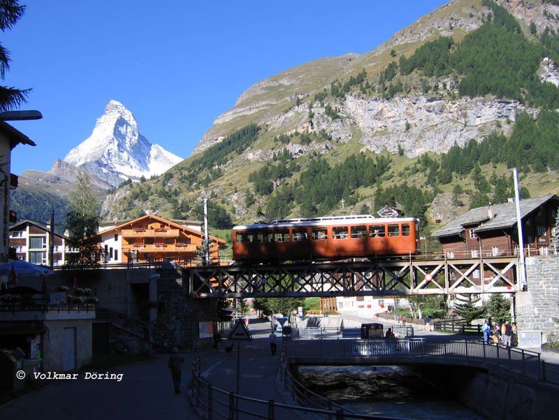 Die langen Schatten am zeitigen Vormittag kitzeln den Altbautriebwagen der Gornergratbahn beim berqueren der Matter Vispa doch dank des herrlichen Wetters ist das 4.489 m hohe Matterhorn klar zu sehen - Zermatt, 17.08.2005
