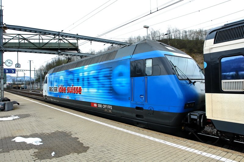 Re 460 020-1. Trotz trbem Wetter leuchtet das Blau der  SRG SSR ide suisse  Werbelok im Bhf. Frick (Kanton Aargau). Wie mag es erst bei Sonnenschein sein ? 25.3.2007