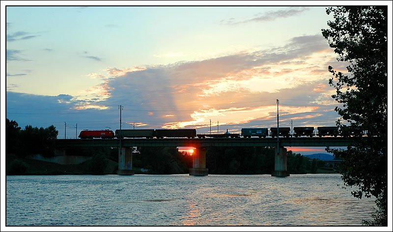 Sonnenuntergang in die Wiener Lobau am 10.8.2007. Eine 1116 (soviel kann ich am Originalbild noch erkennen) fhrt mit einem Gterzug ber die Donau. Ziel ist mit groer Wahrscheinlichkeit der Wiener Zentralverschiebebahnhof.