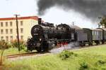 *Modell*
Irgendwo entlang der Mattigtalbahn fährt Mitte der 1950er Jahre die Salzburger 657.1590 mit einem Verschubgüterzug von Braunau am Inn kommend in Richtung Steindorf bei Straßwalchen.
Das Fabrikgebäude ist vermutlich gena ...