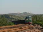 DF4 0412 durchfährt mit einem schweren Güterzug den kleinen Ort Luoyang, der insbesondere für die Longmen-Grotten bekannt ist.