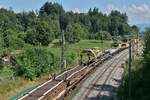 Blick auf die Schwellentransportwagen mit zwei Portalkränen und den Gleisumbauzug MATISA P 95 der SCHWEERBAU am Ende.