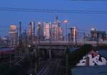 Während ein ICE1 aus Richtung Hanau in den Frankfurter Hbf einfährt, erleuchten die Wolkenkratzer der Frankfurter Skyline im letzten Sonnenlicht.