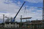 Um die aus dem Jahr 1901 stammende Thierschbrücke am Bahnhof von Lindau durch einen Neubau ersetzen zu können, muss zuerst die alte Brücke abgerissen werden. Am 22.10.2017 zieht ein hinter dem Stellwerk stehender Mobilkran ein zuvor abgetrenntes Teil aus der Brücke, um dies hinter dem Stellwerk für den späteren Abtransport abzulegen.