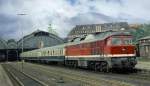 Die 132002 der DR (232) in Lbeck Hbf, vor einem ausfahrbereiten Schnellzug nach Rostock.