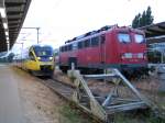 Talent 0005  der OLA mit der Werbung Getrnkeland im Bahnhof von Rostock daneben eine Lok der BR 115 von DB Autozug am 17.07.2010