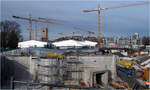 Zelte auf dem Bahnhofsdach - 

Der Einbau der Glasdächer auf den Lichtaugen erfolgt unter einer Einhausung aus Containern mit Zeltdächern. So kann dies witterungsgeschützt gearbeitet werden.

Hinter der Betonwand im Vordergrund liegt die später durch eine Glasgitterschale überdeckte Zugangsebene am Südkopf des neuen Stuttgarter Hauptbahnhofes. Dieser Tunnelansatz rechts unten könnte eine zukünftige direkte ebenerdige Fußgängerverbindung vom Seitenbahnsteig der Stadtbahnhaltestelle Staatsgalerie zum Hauptbahnhof darstellen. Ich weiß es nicht sicher, würde aber Sinn machen.

30.01.2024 (M)