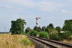 Man könnte fast glauben es würde gleich die Regionalbahn nach Pretzsch kommen aber diese ist bereits seit 1998 hier eingestellt worden.  1998 wurden die durchgehenden Züge nach Eilenburg eingestellt und der letzte Ast von Wittenberg nach Bad Schmiedeberg Ende 2014 eingestellt. Zuletzt gab es hier 2017 Sonderzüge. Ende 2019 wurde die Strecke wegen Oberbaumängeln betrieblich gesperrt. Seitdem verwildern einige Teile der Strecke zusehens. Neben dem Streckengleis befindet sich noch ein hier nicht sichtbares Anschlussgleis zum Leonhard Moll Betonwerk Laußig welches noch bedient wird. Zu diesem Anschlussgleis gehört das Wartezeichen im Hintergrund.

Laußig 13.08.2021