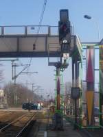 Ks-Asig Y982 am Haltepunkt Potsdam Rehbrcke. Eigentlich nichts Neues. Seit der ESTW-Zeit hat nahezu jeder Haltepunkt wenigstens ein Asig, das direkt am Bahnsteig steht. Selten wird dieses Signal jedoch dadurch, da der gekrpfte Mast der Strecke abgewandt ist, was hier voraussichtlich aus bautechnischen Grnden so angewandt wurde. Die zweite Seltenheit ist das Mastschild: es stammt noch aus den Anfangszeiten der Ks-Signale. Man hatte damals zunchst ganz neue Mastschilder einfhren wollen, jedoch haben sie sich nicht (gnzlich) durchgesetzt. Geblieben ist nur das gelbe Dreieck, das jedes kombinierte Ks-Signal trgt. Rechtsseits habe ich aus einem anderen Foto noch eine etwas grere Darstellung kollagiert.