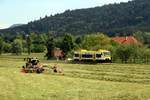 Es wird im Harmersbachtal gearbeitet    Ein Traktor wendet das gemmähte Gras auf einer Wiese, während VT 516 als SWE 72220 vorbeifährt (08.05.0220) 