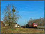 185 198-9 der DB Cargo rollt am 07.04.2018 mit einem bunt gemischten Güterzug durch den ehemaligen Bahnhof Jütrichau. Bis 2012 hielten in dem kleinen Dorf noch die Züge der Linie RB 42, dann wurde der Halt im Zuge des Streckenausbaus aufgelassen. 