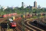 Während 185 397-7 am 04.07.2015 mit einem Containerzug in den Neusser Güterbahnhof einfährt, sind im Hintergrund zwei 440 als S 8 in Richtung Düsseldorf unterwegs