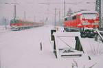 Jahreszeitgemäß gibt's heute noch mal eine Schippe Schnee auf die Mütze: Am 25. Januar 2004 im Bahnhof Freilassing. Ein Nahverkehrszug fährt nach Salzburg. 111 055 wartet auf den nächsten Einsatz.