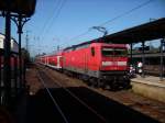 112 138-3 schiebt den RE7 an einen sonnigen Samstagmorgen aus dem Bahnhof Unna heraus in Richtung Hagen.