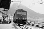 18. Februar 1985: Ein Güterzug nach Bad Schandau durchfährt den Haltepunkt Königstein in der Sächsischen Schweiz.Im Hintergrund auf dem Berg ist die Festung zu erkennen, das Plakat links wirbt für den Besuch.