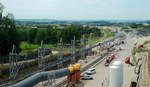 NBS Wendlingen - Ulm: Am 09.07.2017 bot sich dieser Blick von der Besuchertribüne am Tunnelmund des im Bau befindlichen Bosslertunnels bei Aichelberg. Der Tunnel wird 8.806 m der längste der Neubaustrecke sein. Links ist das Förderband zum Abtransport des Tunnelaushubs zu erkennen, in der Mitte die Be-/Entlüftung. Das in der Mitte sichtbare 900 mm-Gleis gehört zur Stollenbahn, die die Tübbinge (vorgefertigte Betonsegmente zur Tunnelversteifung) vom Lagerplatz zur Tunnelvortriebsmaschine transportiert. Auf dem Nebengleis ist ein Bauzug mit Lok L 2 (B-dh Schöma 5740/02 CHL350DCL) abgestellt.