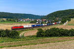 Am 31. Juli 2024 bespannte die 193 328 den KLV-Zug KT 42152 von Verona Q.E. nach Rostock Seehafen. Die Beladung des Zuges wies schon sinnbildlich auf ein zum Aufnahmezeitpunkt kurz bevorstehendes Ereignis hin. Das dänische Transportunternehmen DSV übernahm die Logistik-Tochter der Deutschen Bahn, DB Schenker, für 14,3 Milliarden Euro. Mit dem erzielten Erlös soll die Bahn einen großen Teil ihres Schuldenbergs abbauen. Ob es allerdings tatsächlich auf lange Sicht klug war, den größten Gewinnbringer im Konzern abzustoßen, wird die Zukunft zeigen. Die hier gezeigte Aufnahme entstand in Breitenfurt im Altmühltal.