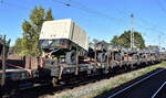 DB Cargo mit Drehgestellflachwagen mit vier Radsätzen, mit Stirnwandklappen, ohne Seitenborde und mit Rungen der Wagengattung Rmms 664, beladen mit einachsigen Militärhängern in einem Militärtransportzug am 15.10.24 Höhe Bahnhof Magdeburg Neustadt.