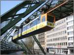 Hier sieht man einen der Gelenkzge der Wuppertaler Schwebebahn aus westlicher Richtung kommend kurz vor Erreichen der Haltestelle beim Hauptbahnhof.