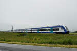 Zwei aneinander gespannte Regionalzüge mit 245 203-5 in der Mitte und 245 202-7 am Ende passiert gleich einen Bahnübergang, so gesehen Anfang Juni 2024 bei Niebüll.