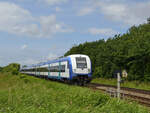 Dieser Regionalzug passiert gleich einen Bahnübergang, so gesehen Anfang Juni 2024 in Klanxbüll.