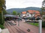 Hier ist der Bahnhof in Bad Herrenalb zu sehen, dem Endpunkt einer der Strecken der Albtalbahn. Die Aufnahme stammt vom 03.10.2002. Jedes Jahr findet hier ein Bahnhofsfest statt, bei dem u.a. regelmig Dampfloks der Ulmer Eisenbahnfreunde zu Gast sind. Zudem finden mehrmals im Jahr Sonderfahrten mit Dampfloks durch das Albtal mit Ziel Bad Herrenalb statt. Deshalb ist hier auch der Wasserkran zu finden. Die Wendeschleife fr die Stadtbahnen verluft um das Bahnhofsgebude herum.