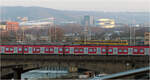 Ein S-Bahn-Band mit einer Stadtbahn oben drauf - 

Parallelfahrt einer S-Bahn auf der Rosensteinbrücke und einer Stadtbahn auf der König-Karl-Brücke in Stuttgart-Bad Cannstatt. 
Im Hintergrund das MHPArena (einst Neckarstadion) und das Mercedes-Benz-Museum im Licht der tiefstehenden der Nachmittags-Wintersonne.

Erfreulicherweise war die Stadtbahn werbefrei. Konzentriert man sich beim Blick auf die S-Bahn auf die roten Bereiche mit den jeweils zwei Fenstern, können diese auch an eine Art Gondeln erinnern, die an einem roten Balken hängen.

18.01.2025 (M)