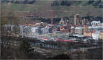 Landschaft, Stadt und Bahn -     Blick auf den Bahnhof Esslingen am Neckar, mit einem dicht bebauten Stadtbereich dahinter der abrupt am steilen Weinberghang endet.