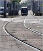 Saarbahn im Gegenlicht -     Eine Bahn auf der Fahrt in Richtung Norden zwischen den Haltestellen Saarbrücken Hauptbahnhof (im Hintergrund erkennbar) und Trierer Straße.