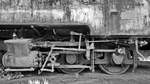 Damfzylinder und Räder an einer ausgedienten Dampflokomotive.
