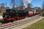 99 2322-8 verlässt den Bahnhof Heiligendamm in Richtung Kühlungsborn mit dem ikonischen Bahnhofsgebäude im Hintergrund - 17.04.2022