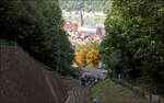 Der Blick öffnet sich entlang der Schneise der Bergbahntrasse -

... hinunter zur Heidelberger Altstadt mit der Heiliggeistkirche und dem Neckar. In der Stationen Schloss findet gerade der Fahrgastwechsel der beiden Wagen statt. Der Königstuhltunnel der Neckartalbahn befindet sich tief unter dem Weichenbereich der Seilbahn.

18.09.2024 (M)