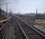 Nieselgrauer Mrztag, der Fotograf  wartet auf einen Zug der Linie S1 aus Dresden nach Radebeul und versucht gegen 15:05 Uhr das Baugeschen - hier Altschotterverladung auf LKW - auf das Bild zu