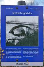 Der Geschichtspfad in Friedrichshafen führt auch zur Schlossbergbrücke, die die Bodenseegürtelbahn überspannt und an der diese Tafel aufgestellt ist (12.03.2021). 
„Am 29.12.1873 wurde durch Staatsvertrag zwischen Baden und Württemberg das Teilstück der Bodensee-Gürtelbahn von Überlingen nach Friedrichshafen beschlossen. Im März 1900 erhielten die Unternehmen Trautmann und Weißflog den Auftrag, den Bahneinschnitt zwischen der Zeppelinstraße und der Schmidstraße auszuheben. Italienische Bauarbeiter realisierten das Vorhaben samt den zwei Brücken über die Bahnlinie im Zuge der Schlossstraße und der Werastraße innerhalb von fünf Monaten.“