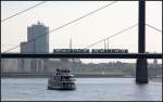 Über den Rhein -     Oberkassler Brücke in Düsseldorf mit Stadtbahnzug, Rheinschiff und Radfahrer.