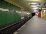 U-Bahnhof Eisenacher Str.: Die Station wurde 1971 von Rmmler gestaltet und erffnet. Sie hat wie viele andere Bahnhfe der Linie auch farbige (hier grne) Platten an den Wnden, die von einem weissen Band unterbrochen sind auf dem der Stationsname abgebildet ist. Ungewhnlich ist die gewlbte Decke und die gelb gefliessten Sttzen.