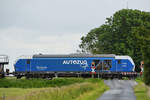 Die Diesellokomotive 247 909  Anne  passiert gerade einen Bahnübergang, so gesehen im Juni 2024 bei Niebüll.