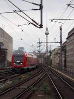 DPE-D 81605 Cottbus - B-Zoo - Potsdam Hbf (- Wustermark Rbf), führend mit WFL DoSto-Stw. 778.4
und geschoben von 143 019, hier kurz vor der Einfahrt in den Bahnhof Friedrichstraße Richtung Westen.
Im Hintergrund das Gebäudeensemble vom Alexanderplatz, Hotel und Fernsehturm.
Aufgenommen vom Bahnsteigende Bahnhof Friedrichstraße.

Berlin, der 26.07.2024