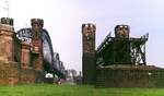 Die Brückentürme der Rheinbrücke(n) Düsseldorf - Neuss Anfang der 1980er Jahre auf der Neusser Seite, im Hintergrund sind am gegenüberliegenden Ufer ihre Düsseldorfer Pendants erkennbar. Dort, wo sich einmal die rechten (südlichen) Brückentürme befanden, verläuft heute die neue viergleisige Rheinquerung. Dagegen blieben die Türme der nördlichen Brücke auf beiden Ufern erhalten.