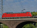 Die Elektrolokomotive 185 144-3 befährt die Hochfelder Eisenbahnbrücke, so gesehen Ende August 2022 in Duisburg.