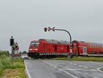 Die Diesellokomotive 245 004 passiert gerade einen geschlossenen Bahnübergang.