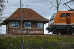 Hinter dem Bahndamm ragt das Stellwerk Stralsund Rügendamm hervor, an dem die Locon Lok 501 auf das Ende der Rangierarbeiten wartet.