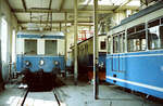 Vier verschiedene Schätze aus der Eisenbahnwelt der nichtbundeseigenen Trossinger Eisenbahn im Bw Trossingen-Stadt: Zunächst evtl. der T3, rechts daneben ganz vorn einer der beiden Esslinger ETs von 1956, der nächste ET ist mir nicht bekannt, und versteckt noch die älteste fahrfähige Ellok Deutschlands, die 1983 noch unrestaurierte Ellok EL4 von 1902. 
Datum: 01.09.1983  