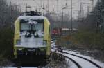 Eine unbekannte ES64U2 der TX Logistik ruht im Schnee whrend 825 der der RBH mit ihren Abraum Zug in den Wanne-Eickler Hbf einfhrt.